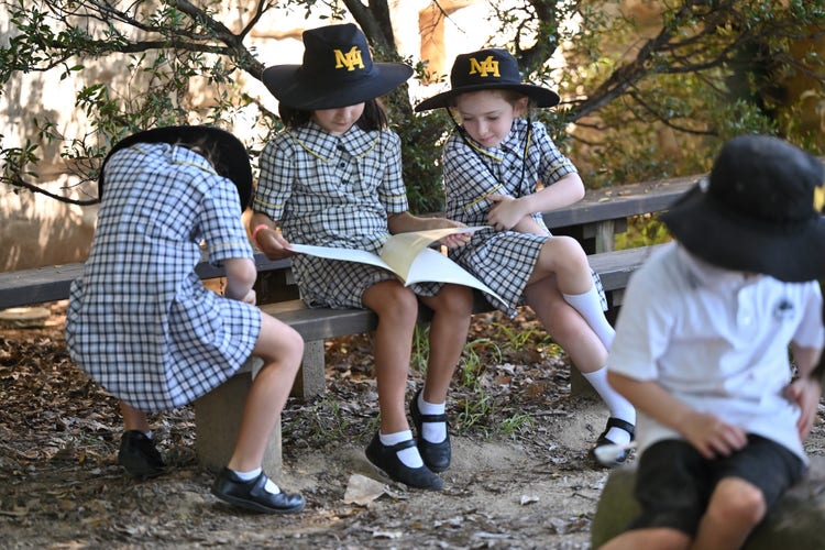 Students sitting on a bench outside reading